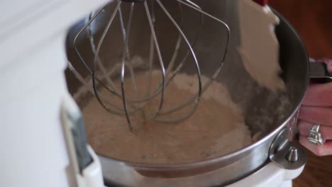 Lowering-a-metal-KitchenAid-counter-top-mixing-bowl-to-scrape-batter-with-a-rubber-spatula,-in-4k-60fps