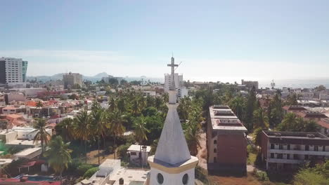 aerial of crucifix on top of church tower overlooking beautiful city in summer