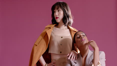 diverse female models stepping into frame creating twin model poses on pink chair in studio