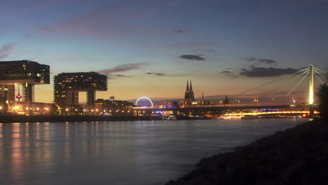 colorful day to night timelapse of colognes crane houses and rhine river in the foreground