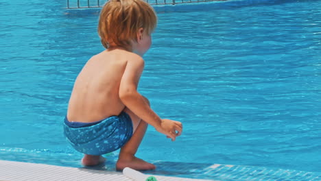 niño feliz sentado cerca de la piscina