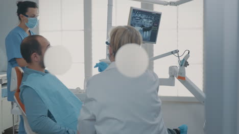 dentist pointing at denture radiography on digital tablet