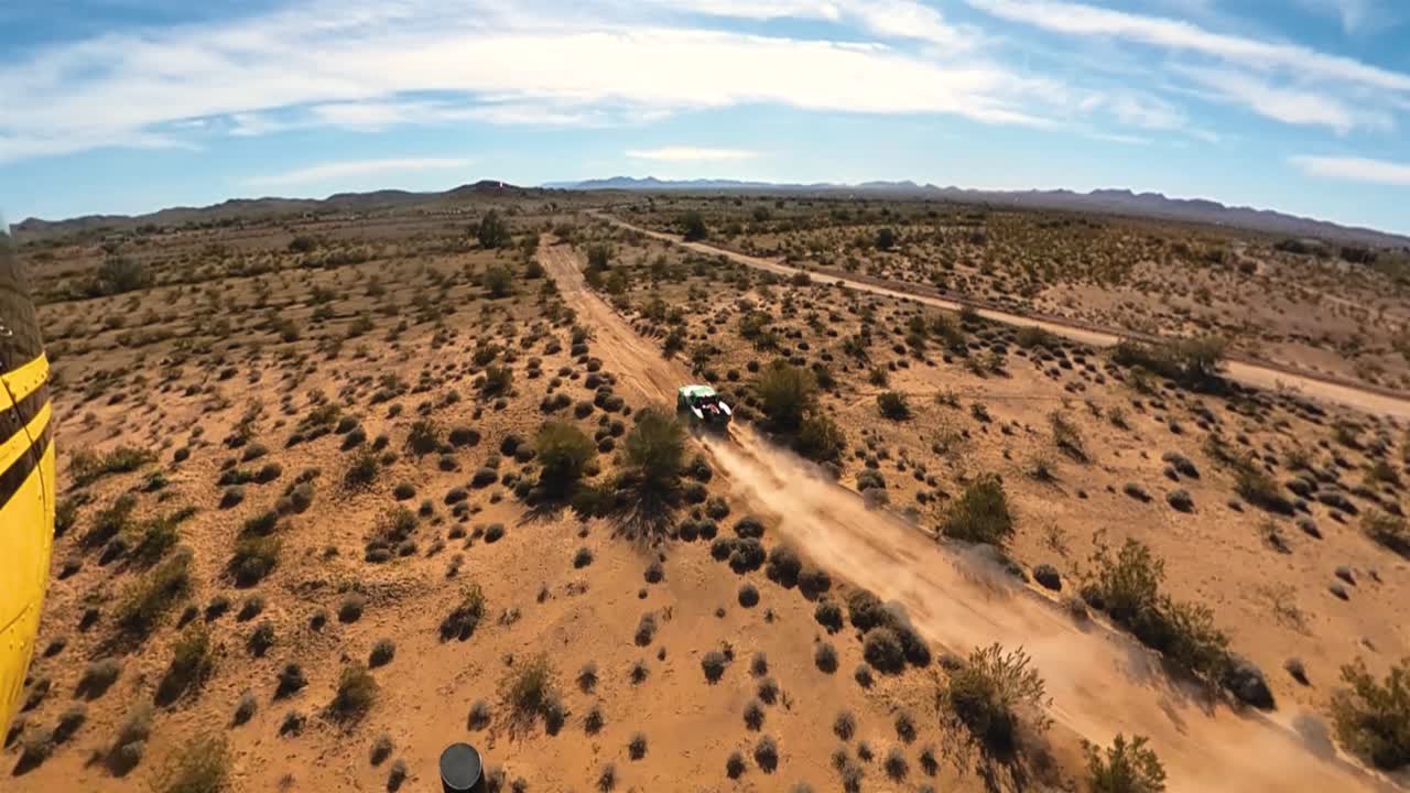 Three sixty view of Green trophy truck racing through desert shot from helicopter