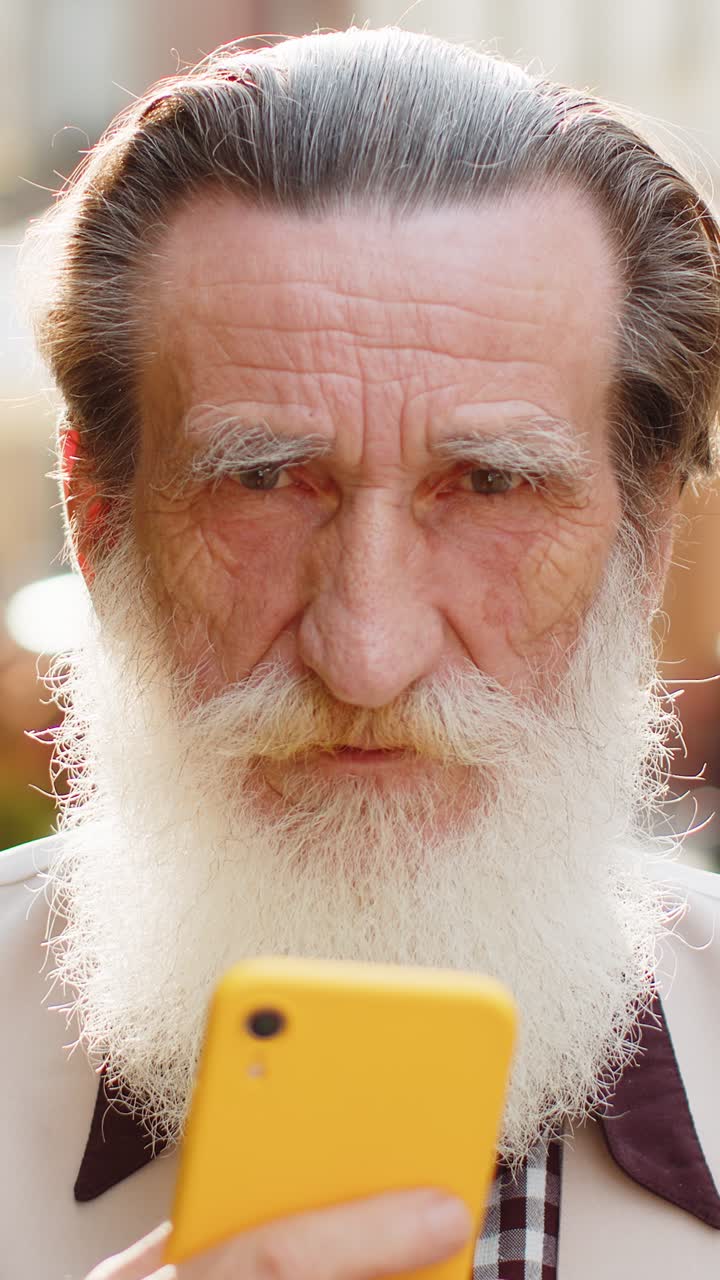 Anziano usa lo smartphone, digita messaggi, naviga su internet, finisce il lavoro e guarda la fotocamera.