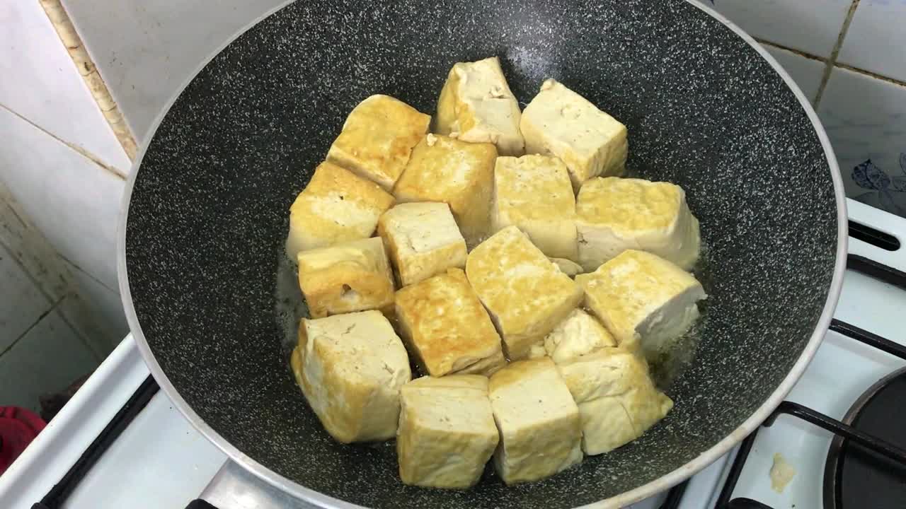 cerrar freír tofu fresco en pan frito antiadherente, vista desde arriba