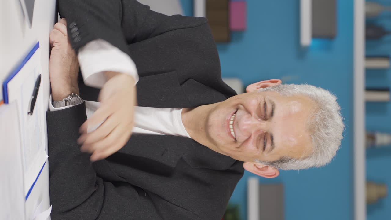 video vertical de un trabajador de oficina en casa saludando a la cámara.