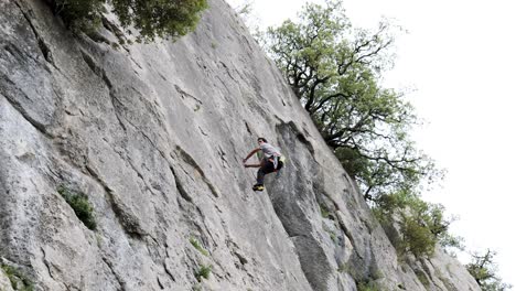 male climber ascending on cliff in summer