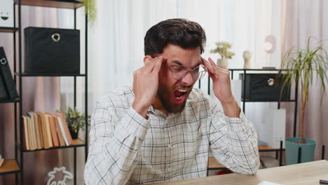 tired ill indian businessman suffering from headache problem tension migraine stress at home office