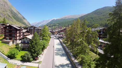 Flying-over-Zermatt-canal-and-overlooking-the-tranquil-and-peaceful-alpine-village-during-the-beautiful-spring-day-in-Swiss-Alps,-Switzerland,-Europe