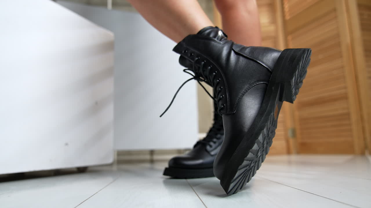 Leather army fashionable stylish black boots demonstrated by the female model. Woman turning her feet in front of camera. Close up.