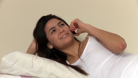 Laughing-woman-lying-on-bed-talking-on-phone