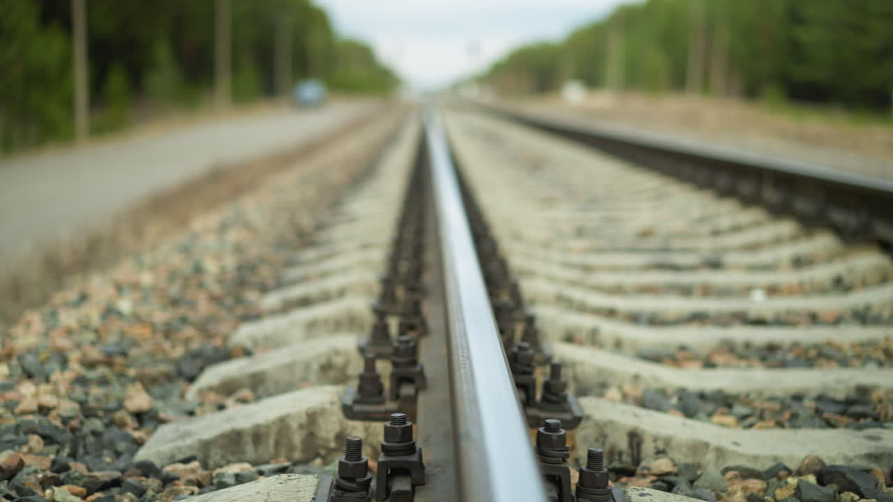 멀리까지 어있는 철도 트랙의 클로즈업 뷰, 촬영은 철도와 그 고정 장치에 초점을 맞추고, 배경은 아름답게 흐릿합니다.