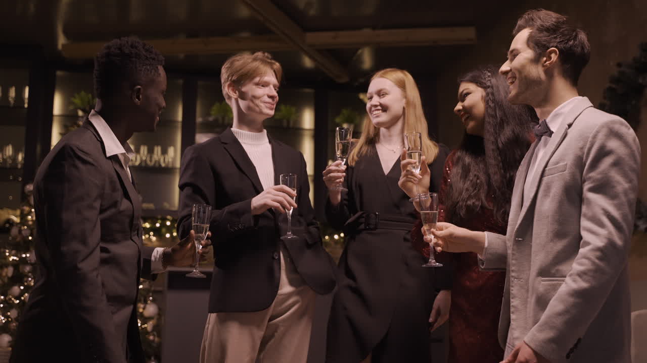 우아한 옷을 입고 샴페인 잔을 들고 신년 파티에서 한 모금을 마시는 친구들