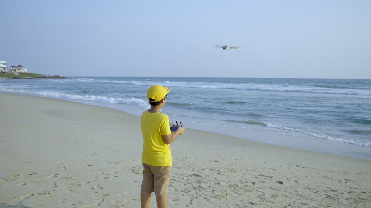 해변 쪽에 드론을 날리는 소년