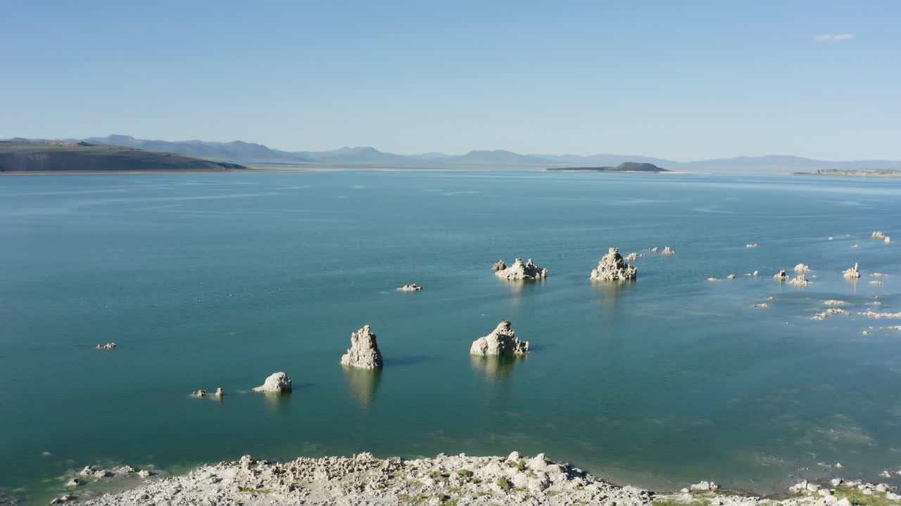 푸른 하늘 아래 광활하고 조용한 풍경으로 둘러싸인 물에서 어나오는 독특한 투프 형태의 모노 호수 (mono lake) 의 공중 풍경