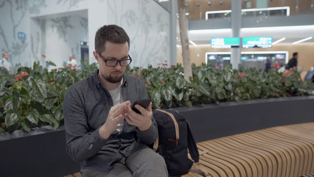 hombre usando un teléfono inteligente en una terminal del aeropuerto