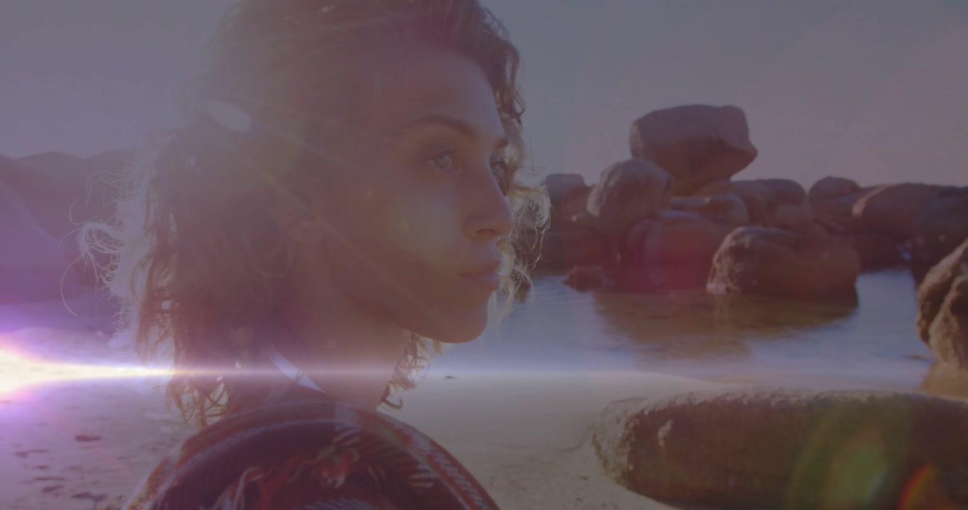 Sunset lens flare sweeping sea initiating woman turning head toward far rocks conveying travel vibe