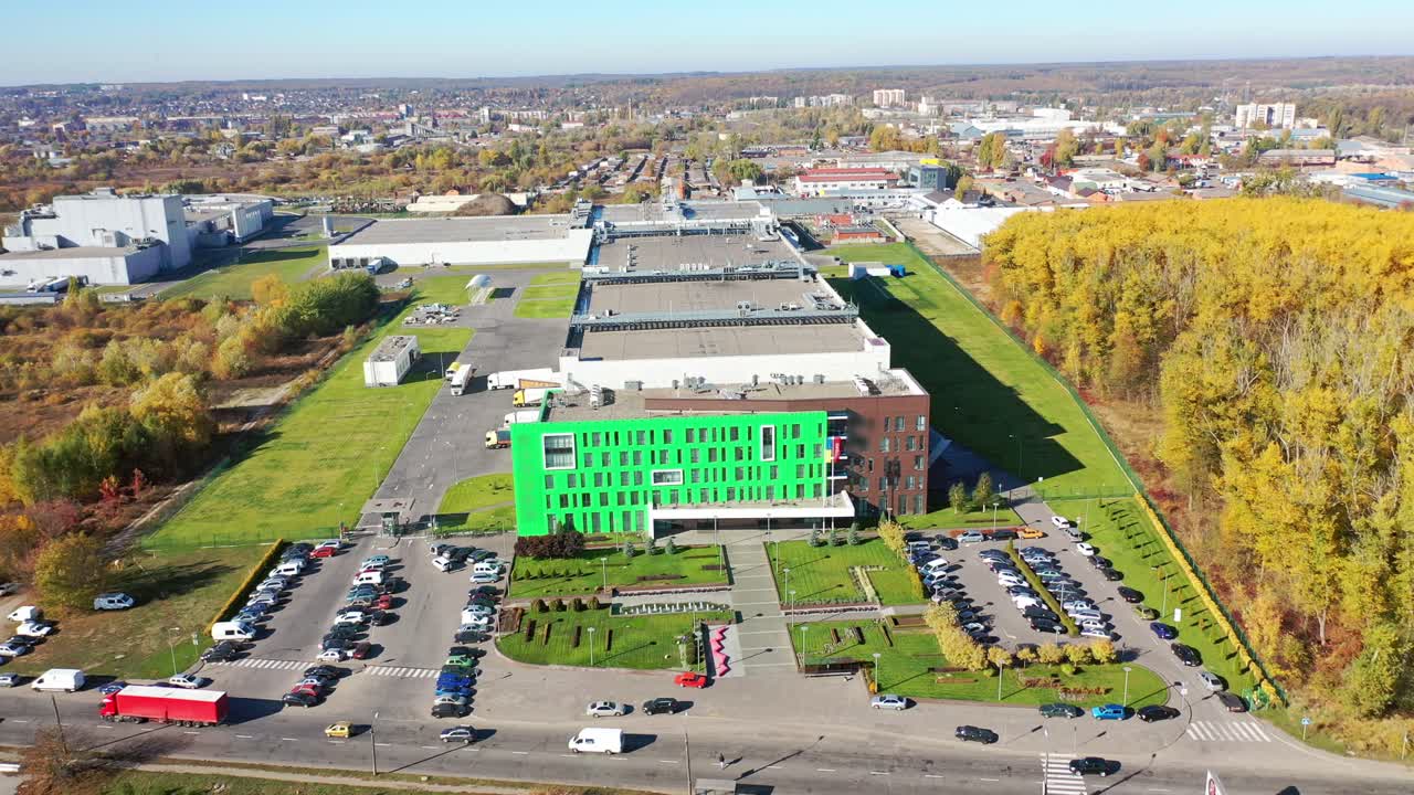 Big factory from bird's eye view. Exterior of a modern plant with many parking places. Contemporary complex on the city background. Aerial view.