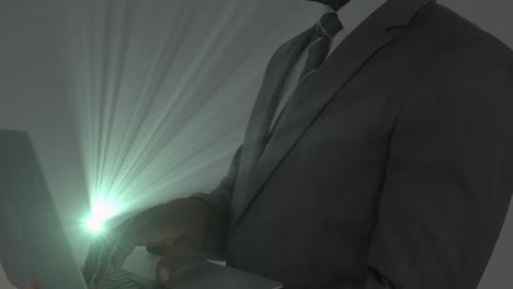 Animation-of-light-trails-over-african-american-businessman-using-laptop