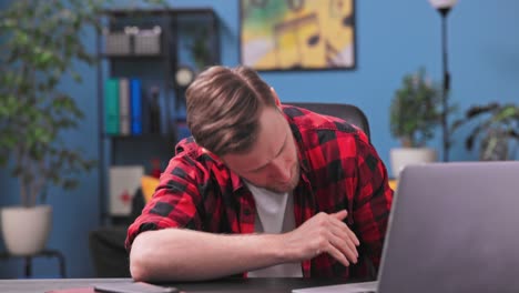 a tired and bored teenage student boy yawns and falls asleep sitting in a chair in his room