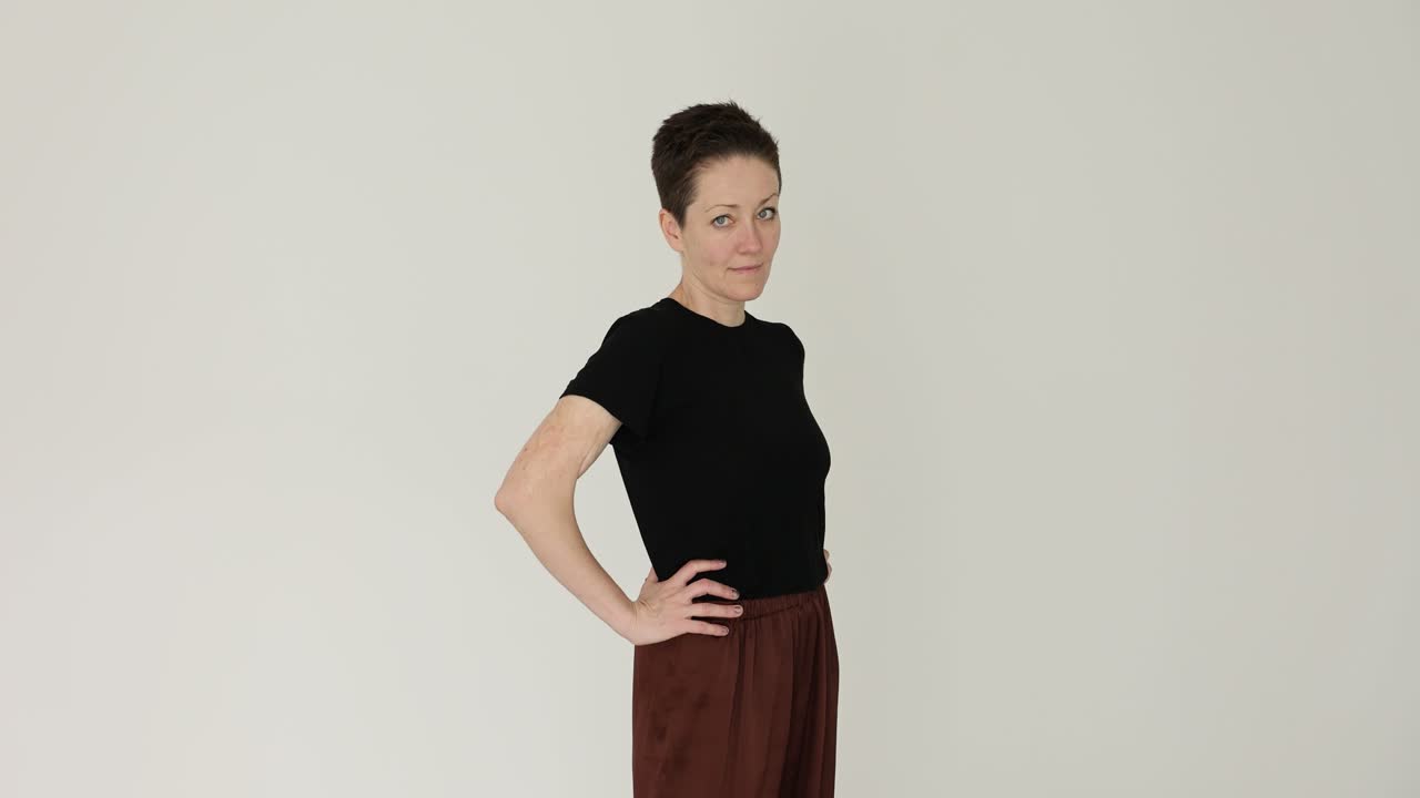 Portrait of a woman with short hair in a black t-shirt and brown pants
