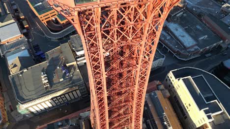 Aerial-drone-flight-around-Blackpool-Tower-circling-the-long-tall-tower-looking-downwards-at-the-rooftops-and-streets-below