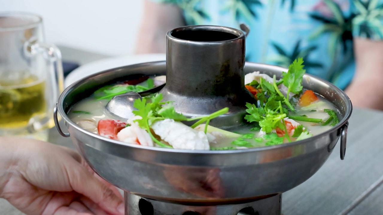 Cận cảnh món súp tom yum bốc khói với tôm và rau mùi trong nồi kim loại