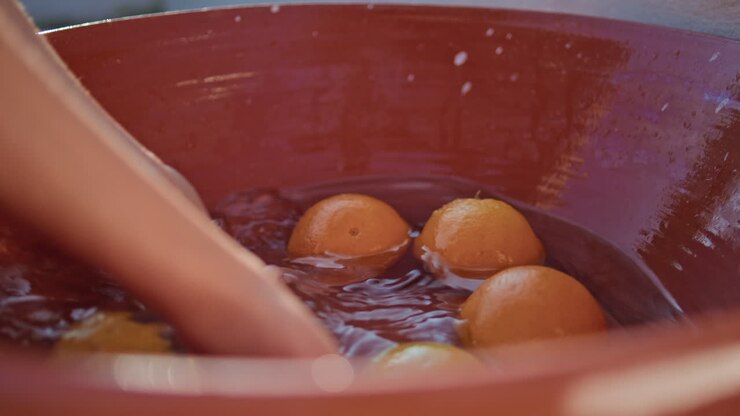 Girl hands cleaning oranges at ceramic bowl closeup. Woman washing ripe citruses