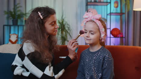 Teenage-child-helps-to-do-face-cosmetic-makeup-her-little-sibling-sister-kid-girls-at-home-play-room
