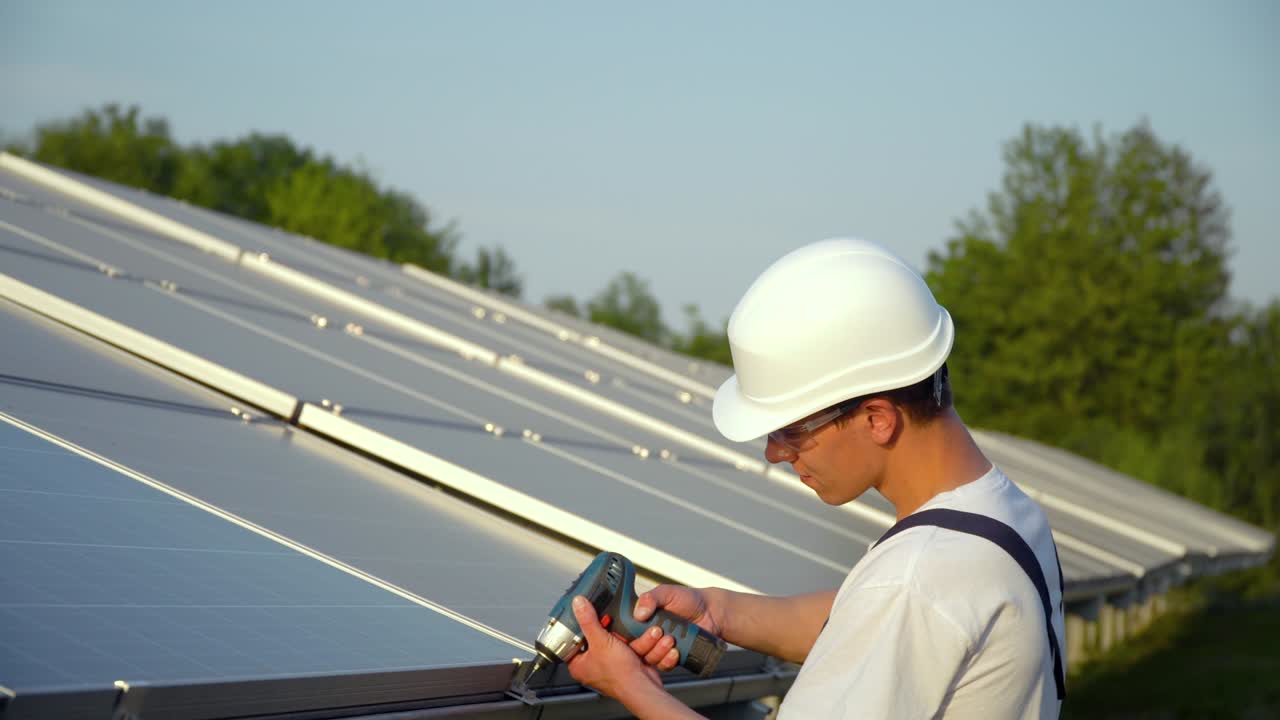 trabajador con uniforme y sombrero instalando paneles fotovoltaicos en una granja solar. concepto de energía renovable