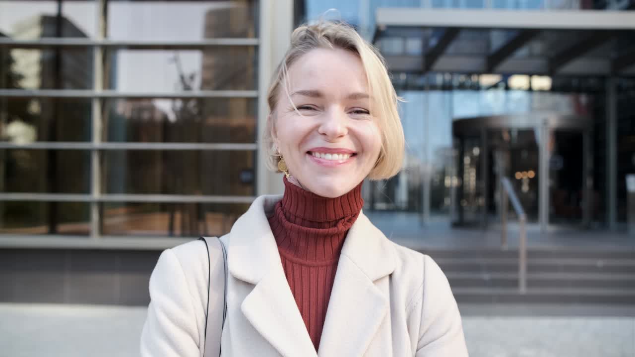 una mujer de negocios confiada posando con los brazos cruzados contra un edificio de oficinas en el distrito de la ciudad financiera.
