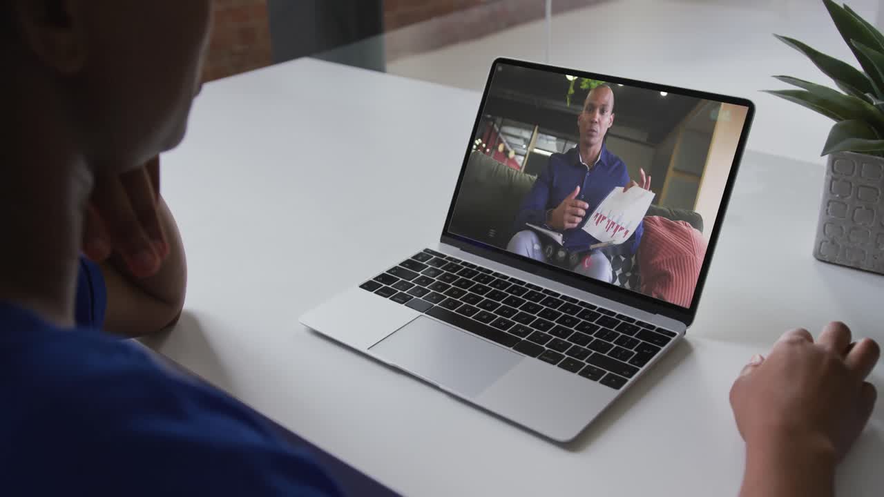 African american businesswoman sitting at desk using laptop having video call with male colleague
