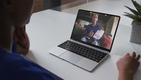 African-american-businesswoman-sitting-at-desk-using-laptop-having-video-call-with-male-colleague