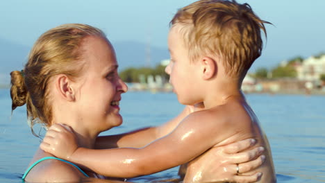 niño besando y abrazando a su madre en el mar