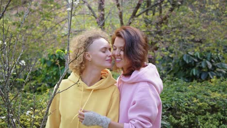 two women kissing in a spring park