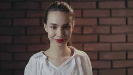 sensual woman biting red lips and looking into camera on brick wall background