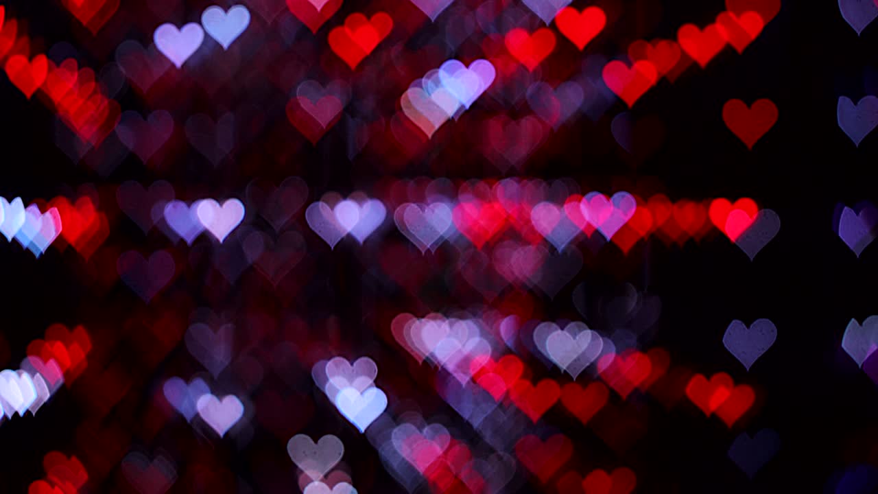 4k uhd video de fondo para el día de san valentín. frontera con bokeh de corazones románticos brillantes y relucientes en un fondo negro. amor, bokeh en forma de corazón.