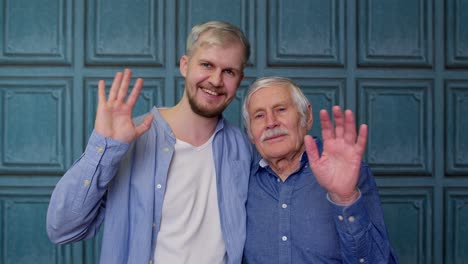 happy different male generations family of senior father and adult son or grandson waving hi, hello