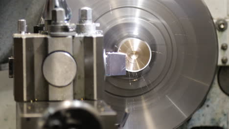 Metal-lathe-in-action,-cutting-a-cylindrical-piece-of-metal,-sparks-flying,-close-up