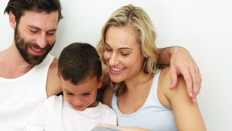 familia linda sonriendo y sentada en una cama