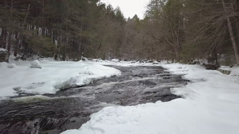 Drone-flying-low-above-snowy-river-rapids