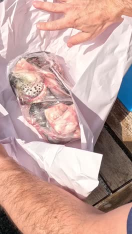 two people collaboratively unwrapping packaged seafood