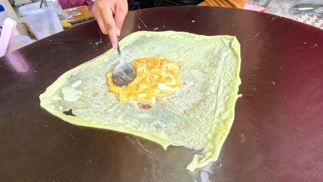 vendor prepares dough with filling on hot pan