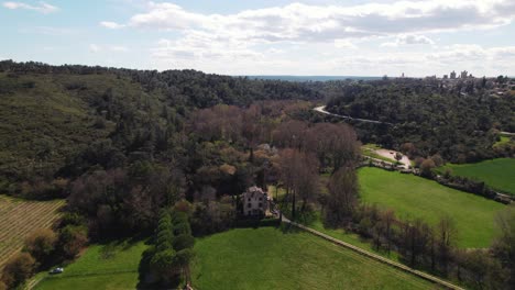 Luftaufnahme-Einer-Burg-Mit-Weinreben,-Wiesen-Und-Einem-Bach-Mit-Blick-Auf-Die-Stadt-Uzes