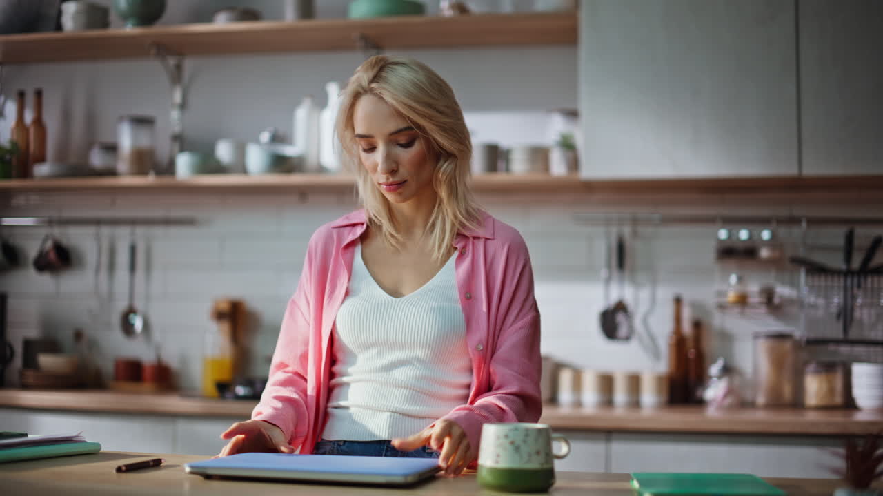 Morning businesswoman opening laptop starting work day kitchen counter closeup