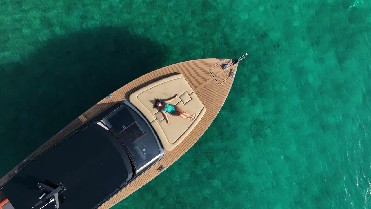 Woman Sunbaths on Yacht Deck, Turquoise Sea, Aerial Top Down Dolly Out