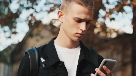 young student using mobile phone outdoors.