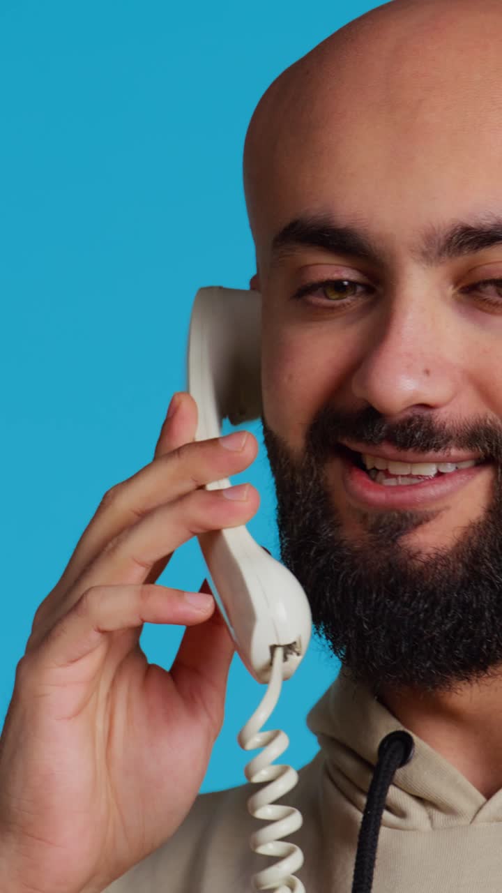 Vídeo vertical de um homem do Oriente Médio falando com pessoas em uma ligação telefônica fixa