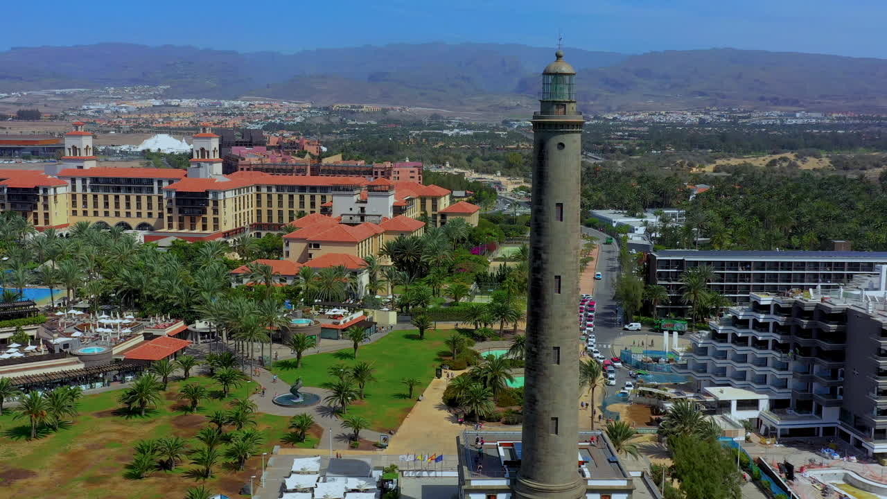 Flying near a lighthouse, beautiful seashore full of resorts, tropical view