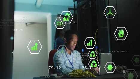 Animation-Digitaler-Symbole-Vor-Einem-Afroamerikanischen-Männlichen-Ingenieur-Mit-Laptop,-Der-Im-Serverraum-Arbeitet